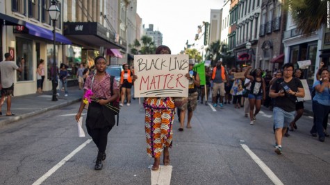 A woman holds a sign in the streets of downtown Charleston